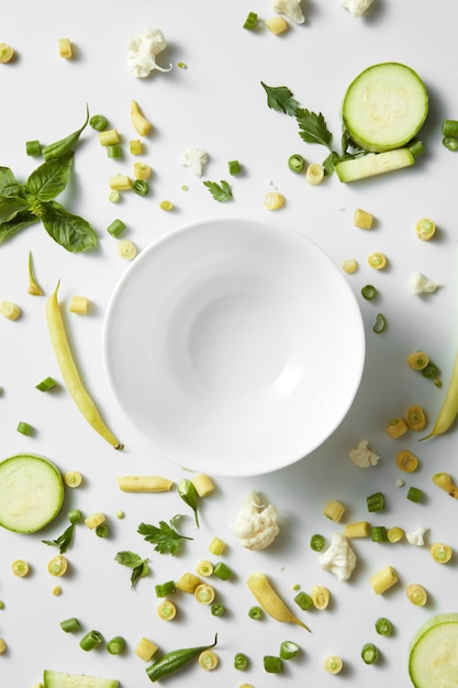 Schließen Sie oben von grünem Gemüse und Obst auf dem Teller für weißen Tisch. Gesunde Ernährung und Essen für Veganer