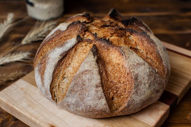 Schließen Sie oben von hausgemachtem Vollkorn-Sauerteigbrot auf Holzbrett