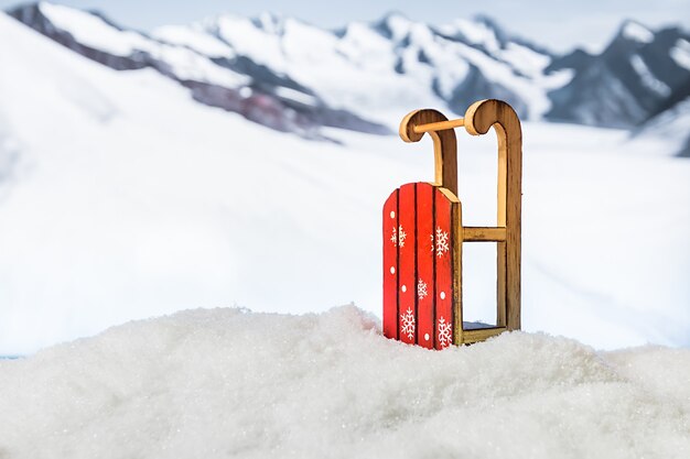 Schlitten in einer Schneeverwehung vor der Winterweihnachtsoberfläche der schneebedeckten Berge