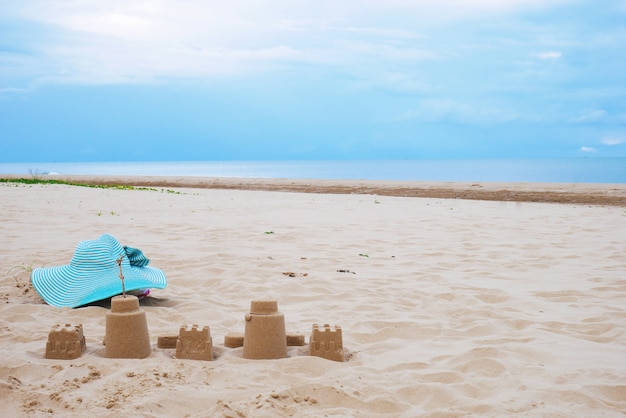 Schlosssand und blauer Hut auf Strand unter blauem Himmel