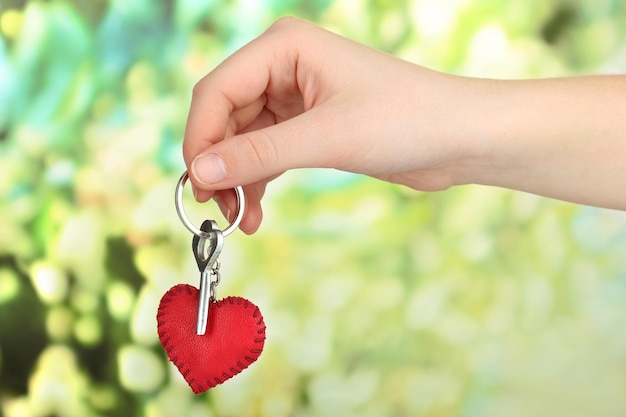 Schlüssel mit Lederschmuck in der Hand auf hellem Hintergrund