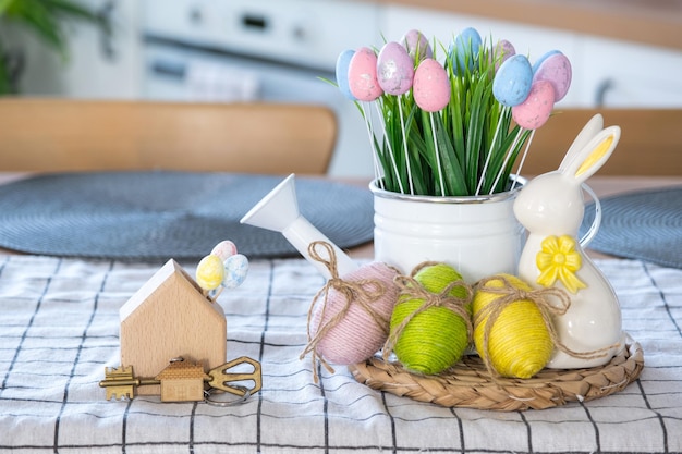 Schlüssel zum Haus des gemütlichen Hauses mit Osterdekor mit Hasen und Eiern auf dem Tisch der Küche Gebäudedesignprojekt Umzug in neue Haushypothekenversicherung Miete und Kauf von Immobilien