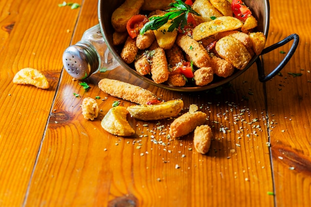 Schmacken Sie gebratene Kartoffelkeile im kupfernen Gerät auf Holztisch