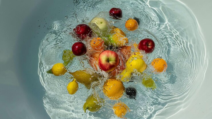 Schmackhafte Obst- und Gemüsefragmente fallen ins Wasser