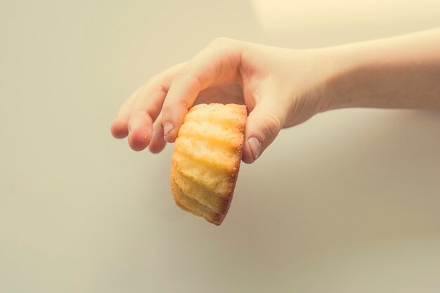 schmackhafter kleiner Osterkuchen auf der Hand eines Kindes auf einem hellen Hintergrund