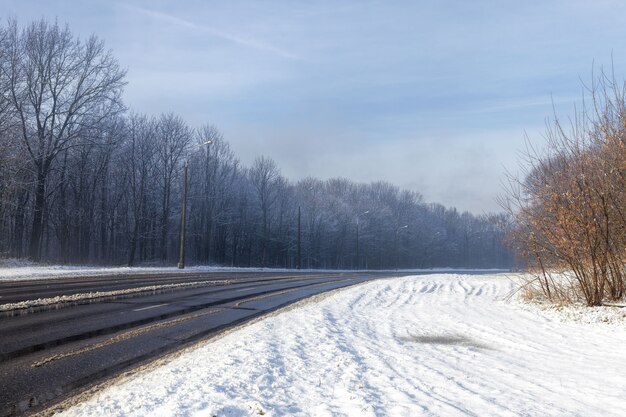 Schmale asphaltierte schneebedeckte Winterstraße für den Autoverkehr