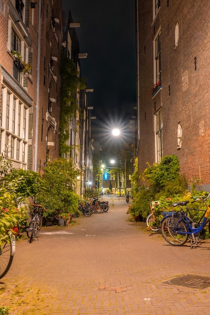 Schmale Straße von Amsterdam bei Nacht und mehrere Fahrräder