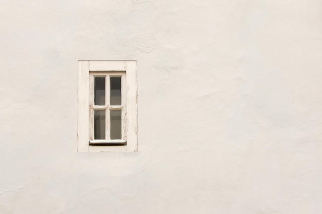 Schmales Fenster mit weißem Rahmen auf dem Hintergrund der weißen Steinwand