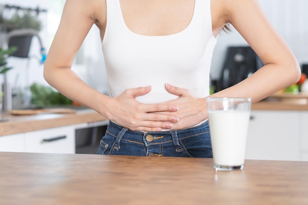 Schmerzallergie asiatische junge Frau Mädchen Hand im Bauch leiden nach einem Glas Milch unglücklich und schlechte Magenschmerzen Laktoseintoleranz und Gesundheitsproblemkonzept für Milchprodukte