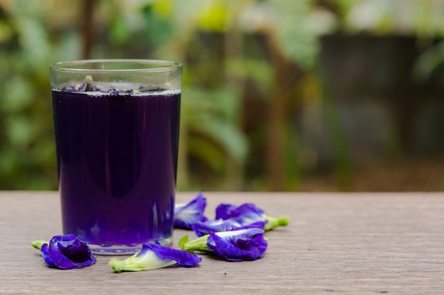 Schmetterlingserbsensaft und Schmetterlingserbsenblume auf hölzernem Hintergrund