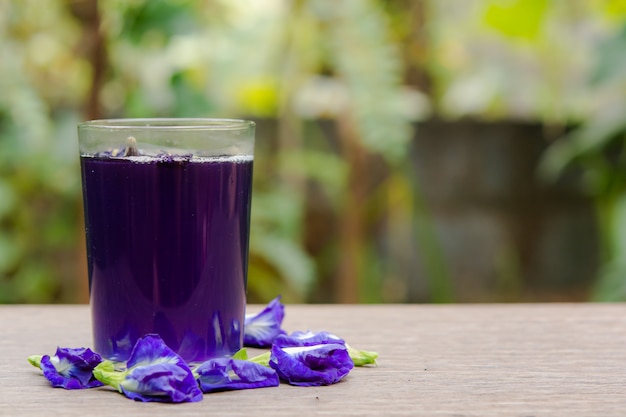 Schmetterlingserbsensaft und Schmetterlingserbsenblume auf Holz