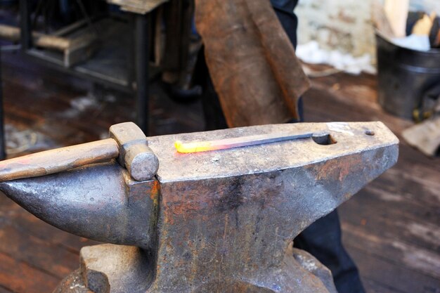 Schmied, der Metall mit Hammer auf dem Amboss in der Schmiede bearbeitet