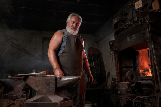 Schmied Handwerker in Schürze arbeitet in der Schmiede