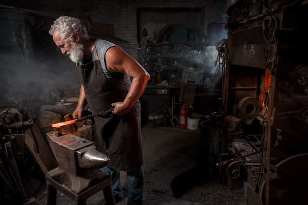 Schmied Handwerker in Schürze arbeitet in der Schmiede