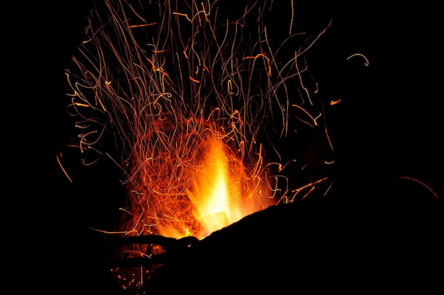 Schmiedefeuerflammenspitzen mit Funkennahaufnahme auf dunklem Hintergrund