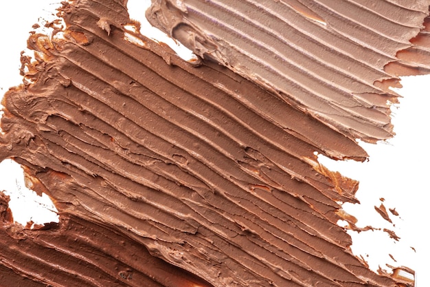 Schmiere von dunkler Creme-Kosmetik-Foundation, isoliert auf Weiß