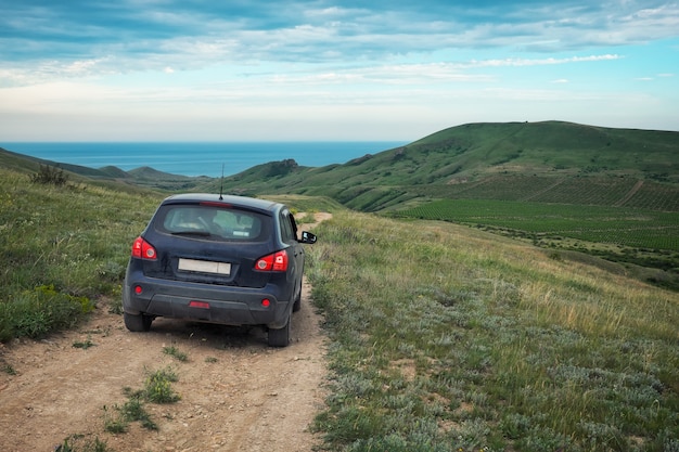 Schmutziges Auto-Crossover. Felder mit Weinbergen. Schöne Natur mit Hügeln. Schwarzes Meer im Hintergrund.