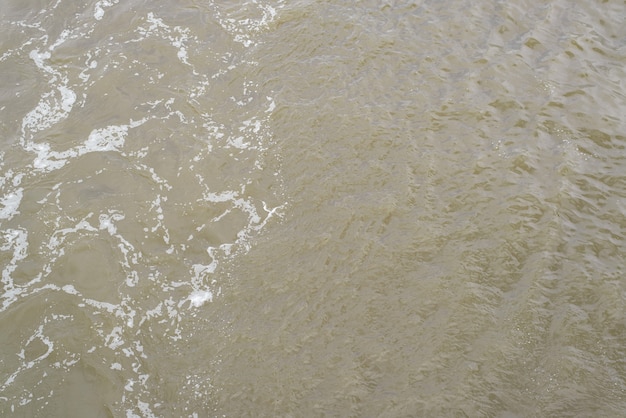 Schmutziges braunes Wasser eines Flusses oder Meeres mit Schaum, Abwasserspritzern, Draufsicht