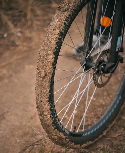 Schmutziges Fahrradrad im Schlamm Schlammiger Mountainbike-Reifen bei extremen Outdoor-Aktivitäten Nahaufnahme des Vorderrads mit Ton darauf