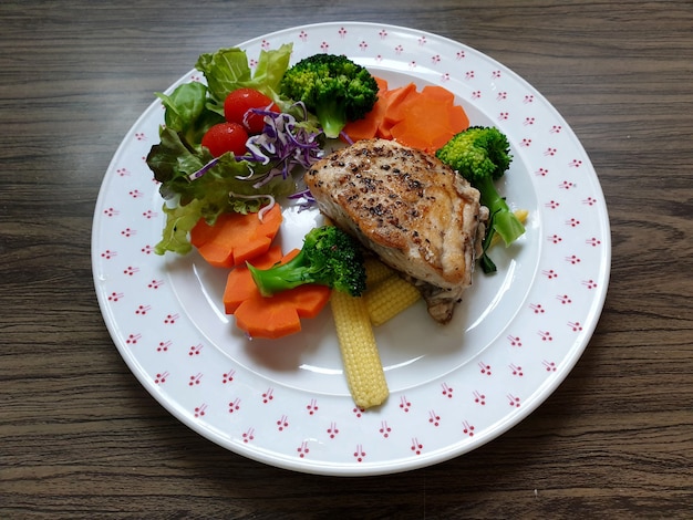 Schnapper-Fischsteak mit Brokkoli-Karotten-Baby-Mais-Tomaten-Salat Rotkohl auf einem weißen Teller