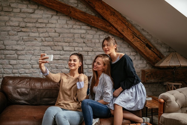 Schnappschuss einer Gruppe Freundinnen, die im Wohnzimmer ein Selfie machen