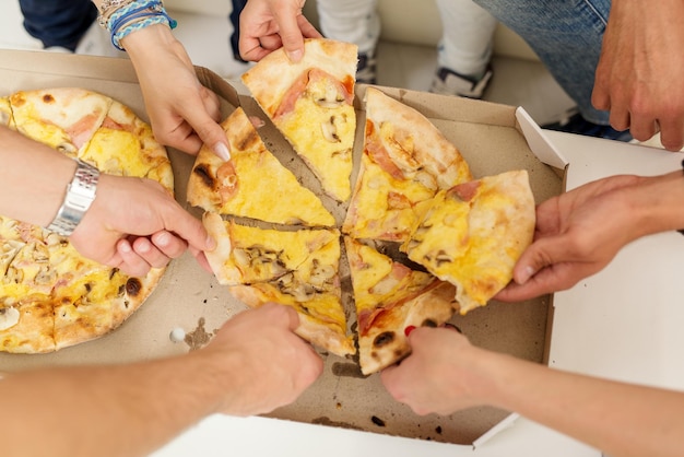 Schnappschuss einer Gruppe von Freunden, die zusammen Pizzastücke essen.