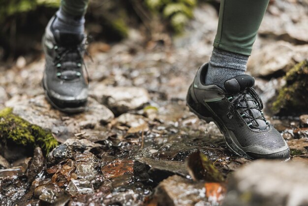 Schnappschuss einer nicht erkennbaren Wanderin, die beim Erkunden des Waldes einen Bach überquert.