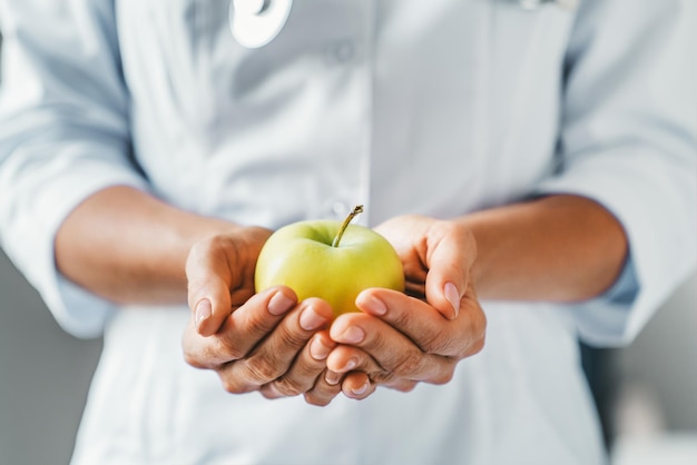 Schnappschuss einer Ärztin, die in einer Klinik einen Apfel mit beiden Händen hält