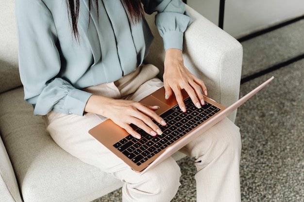 Schnappschuss einer schönen Asiatin, die mit einem Laptop auf dem Sofa arbeitet