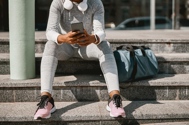 Schnappschuss einer Sportlerin mit Smartphone auf einer städtischen Straße