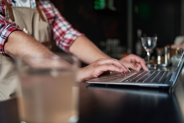 Foto schnappschuss eines jungen baristas, der sich notizen macht und einen laptop benutzt