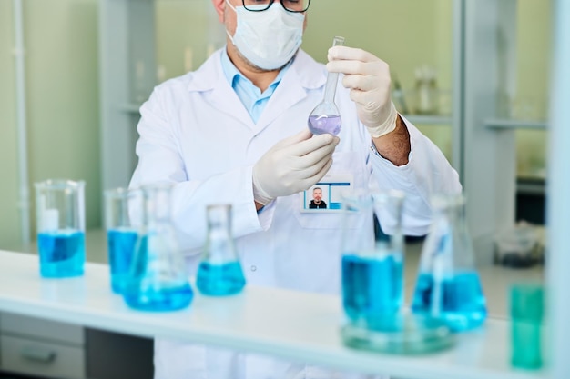 Schnappschuss eines männlichen Pharmakologen, der ein Reagenzglas mit flüssiger Substanz hält
