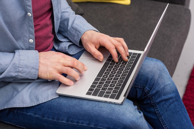 Schnappschuss eines Mannes, der mit Laptop auf der Couch arbeitet