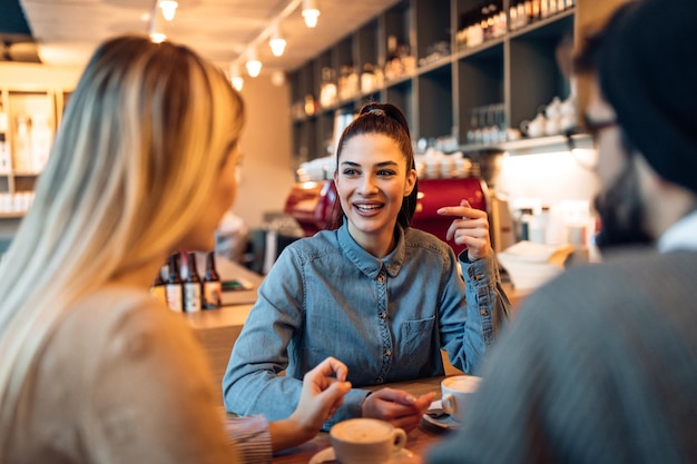 Schnappschuss von drei Studenten, die sich in einem Café unterhalten