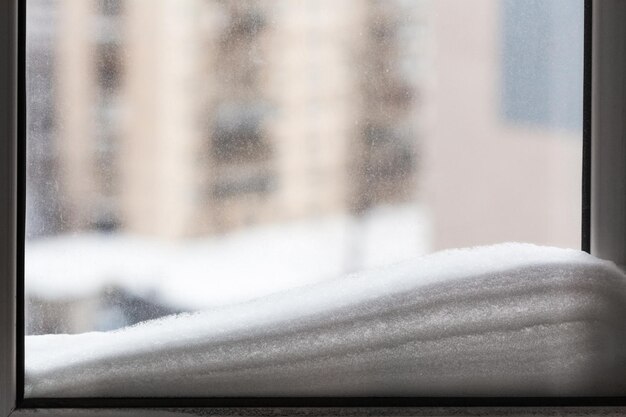 Schnee auf der Fensterscheibe und Häuser im Hintergrund