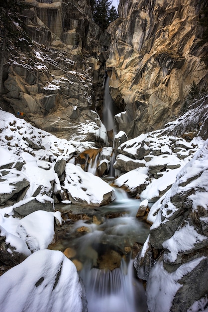 Schnee auf Felsen im Winter neben einer Höhle in den französischen Alpen