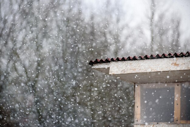 Schnee fällt auf das Dach des Hausesdas Konzept des schlechten Wetters im Frühjahr