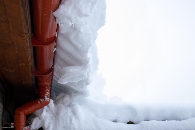 Schnee fällt vom Dach des Hauses Winterwetter mit starkem Schneefall