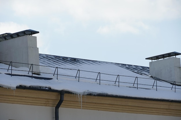 Schnee und Eis auf den Dächern von Gebäuden Eiszapfen hängen von den Dächern der Häuser Die Wahrscheinlichkeit, dass das Dach unter der Last des Schnees einstürzt