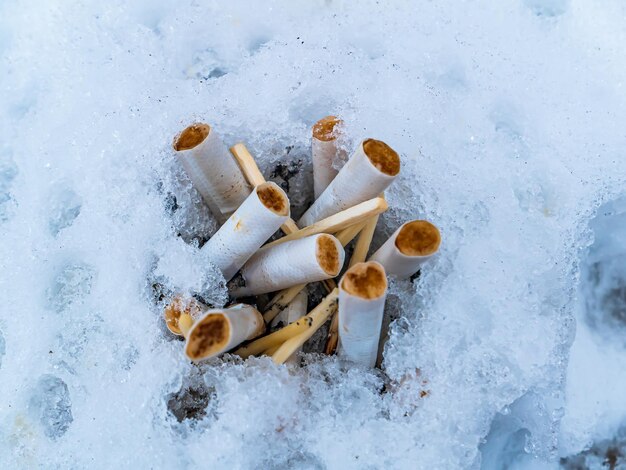 Schneeaschenbecher mit Zigarettenkippen und Streichhölzern