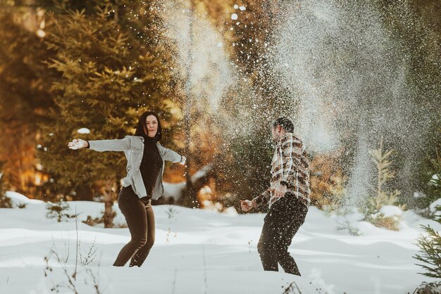 Schneeballschlacht Winterpaar, das Spaß beim Spielen im Schnee im Freien hat Junge fröhliche glückliche Liebhaber Selektiver Fokus