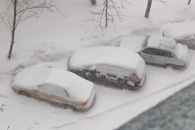 Schneebedeckte Autos auf dem Parkplatz im Schneesturm