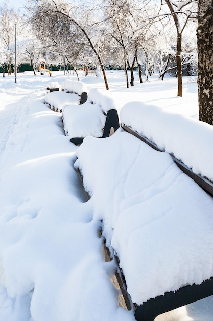 Schneebedeckte Bänke im Garten an sonnigen Wintertagen