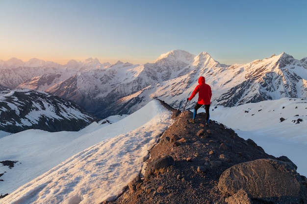 Schneebedeckte Gipfel bei Sonnenaufgang mit einsamem Mann am dunklen Rand des Berges Kaukasus Russland