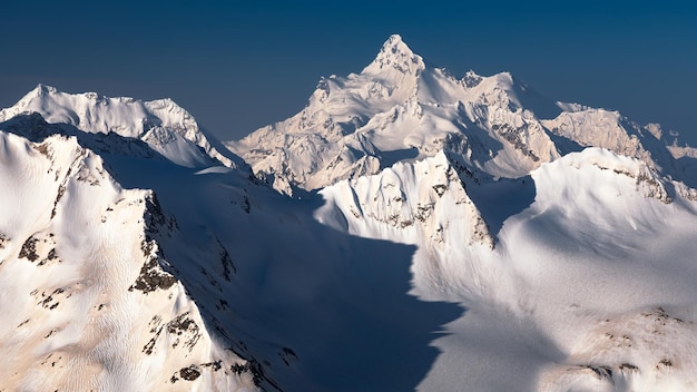 Schneebedeckte hohe Berggipfel mit tiefen Schatten gegen den klaren blauen Himmel Kaukasus Russland