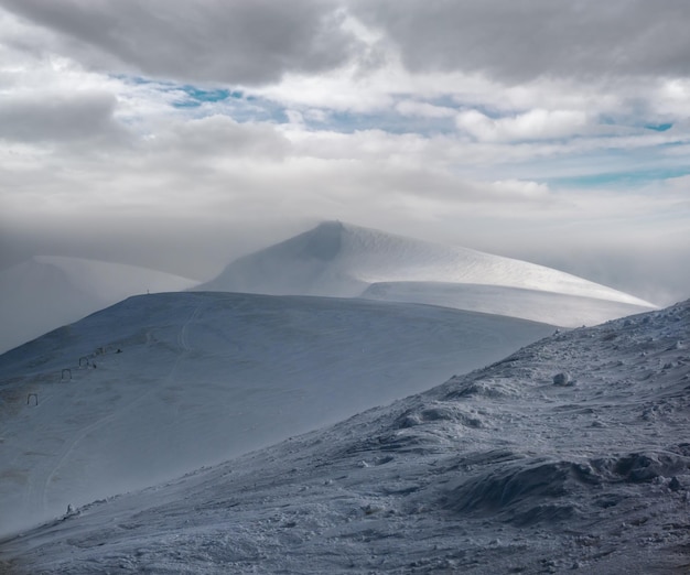 Schneebedeckter Berghang im letzten Abendsonnenlicht herrliche windige Dämmerung auf den Gipfeln über dem malerischen alpinen Skigebiet Dragobrat Ukraine Karpaten