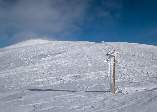 Schneebedeckter Zeiger in der Nähe des Pfades auf einem schneebedeckten Bergplateau Herrlicher sonniger Tag auf dem malerisch schönen Alpenkamm