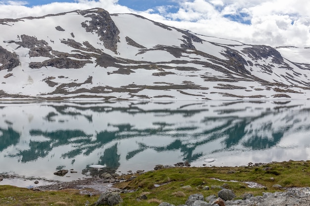 Schneeberge, umgeben von Wolken im norwegischen Fjordreflex im Wasser