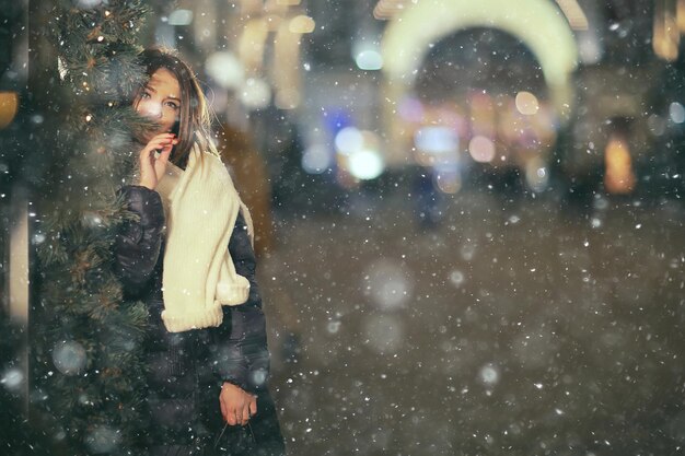 schneefall frau stadt weihnachten draußen, stadtporträt im schneefall, junges modell, das im festlichen blick aufwirft