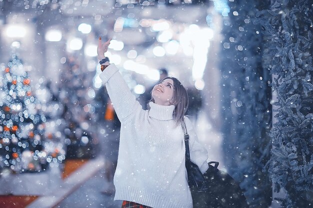 schneefall frau stadt weihnachten draußen, stadtporträt im schneefall, junges modell, das im festlichen blick aufwirft